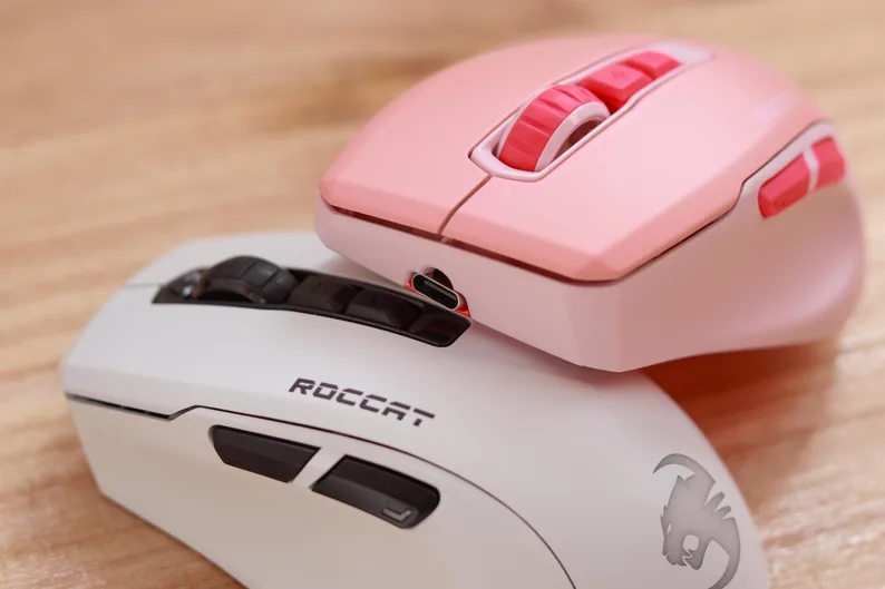 White and pink Roccat Kone Pure Ultra mice stacked together on a light wood surface